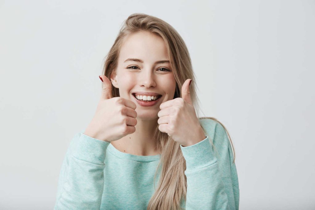 portrait-positive-blonde-female-woman-with-broad-smile-thumbs-up